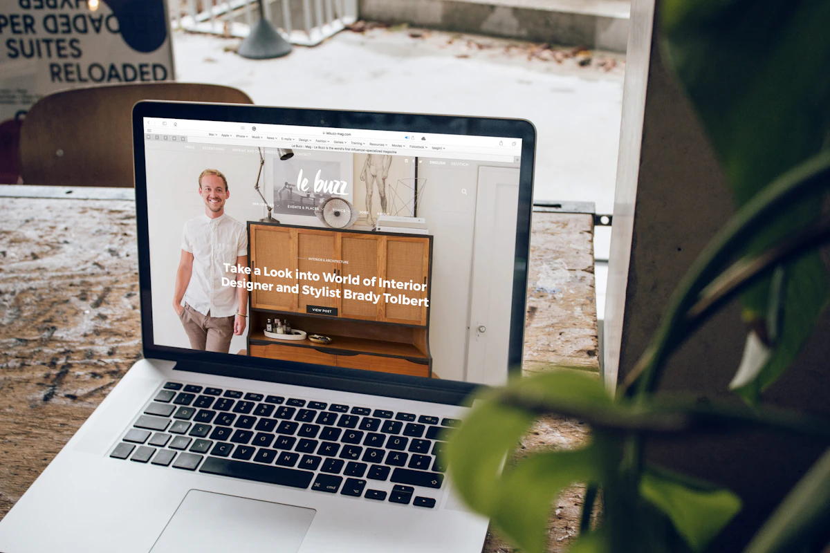 Portátil numa mesa de madeira a mostrar o site de uma empresa, com uma planta ao lado
