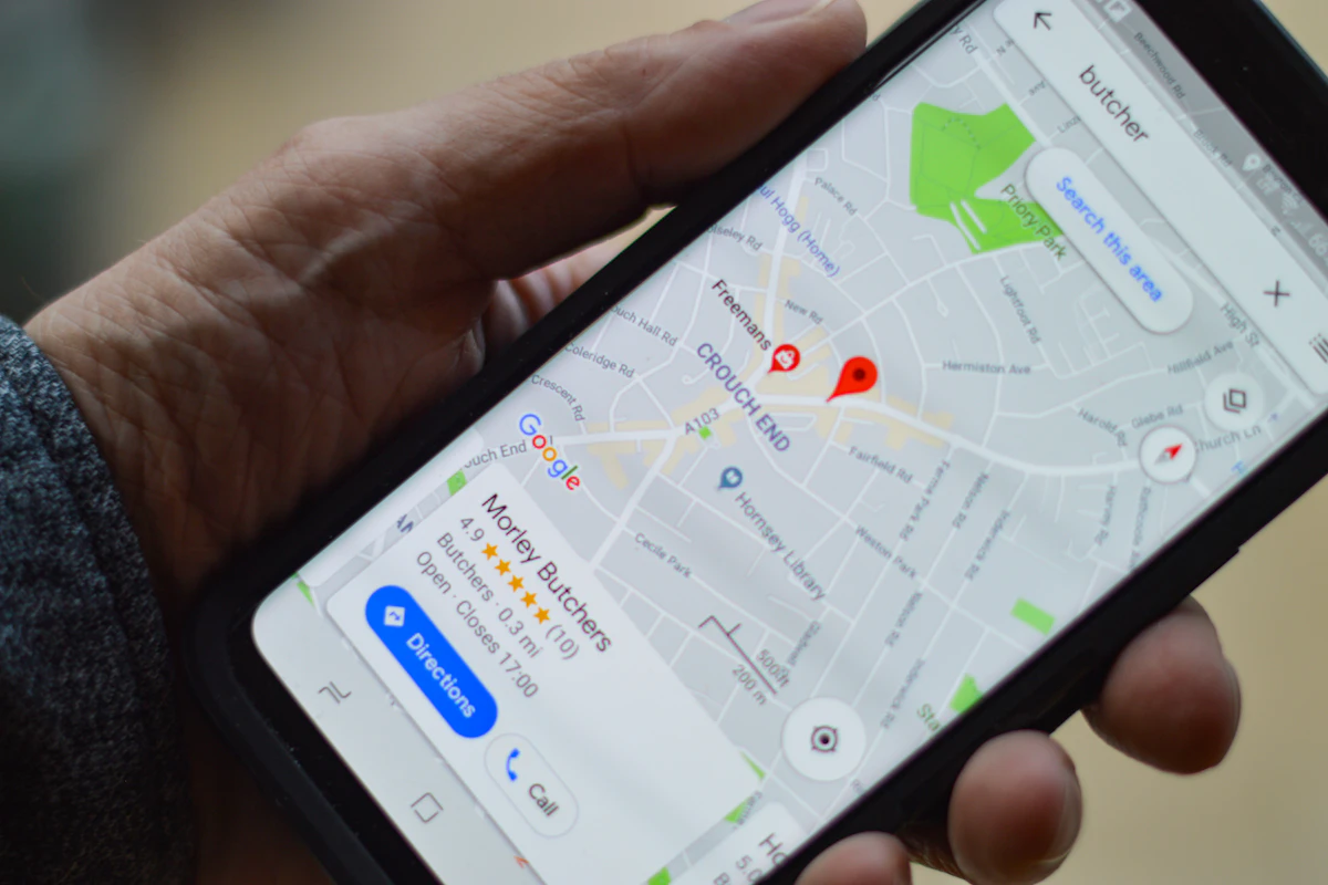 Mão a segurar um telemóvel com o Google Maps aberto e um marcador vermelho no mapa