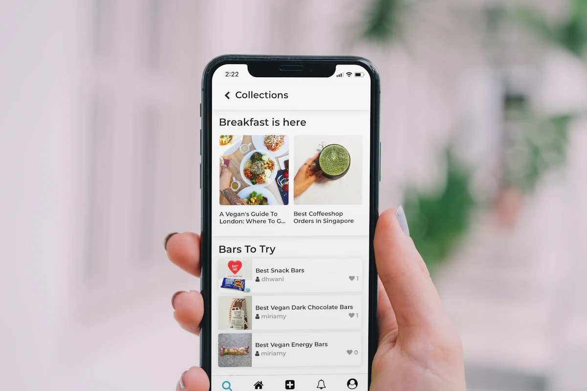 Mão a segurar um telemóvel com uma app aberta numa lista de produtos com fotografias