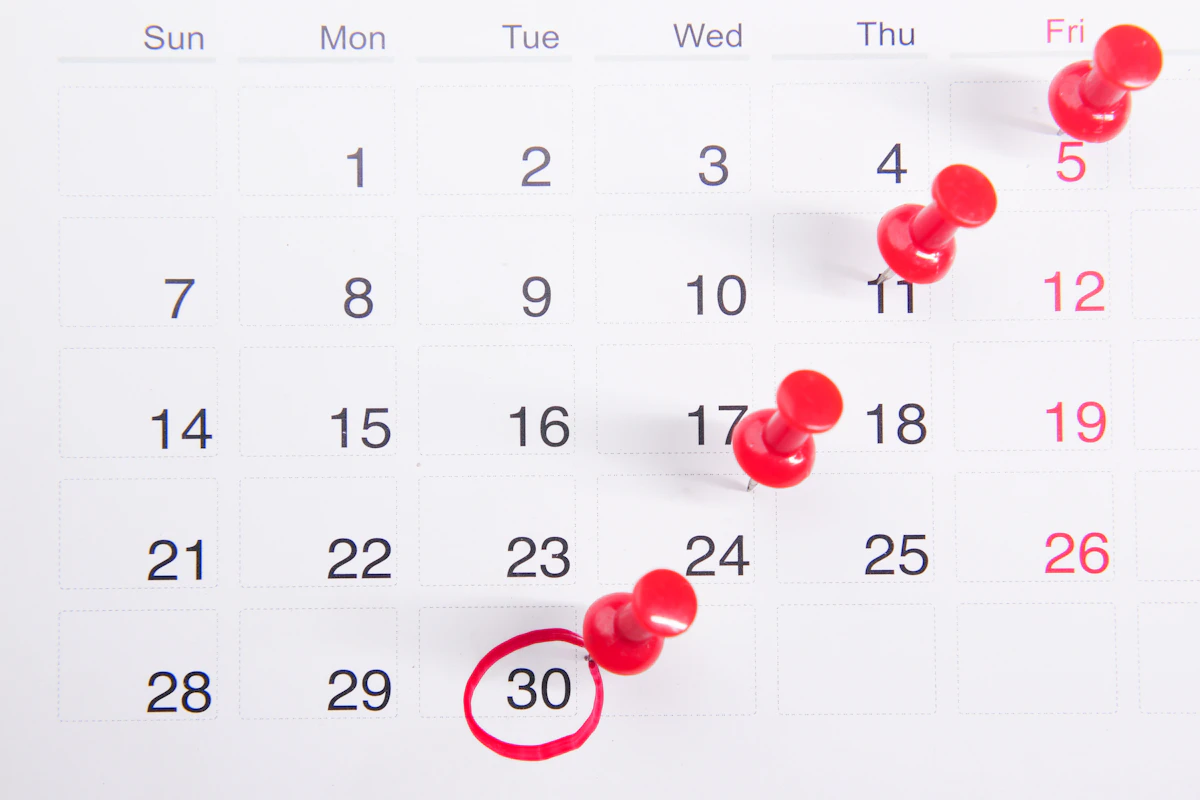 Calendário de mesa com pioneses vermelhos a marcar vários dias e um dia assinalado a vermelho