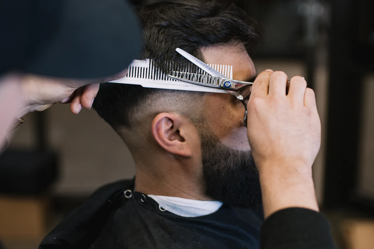 Barbeiro a cortar o cabelo de um cliente com uma tesoura