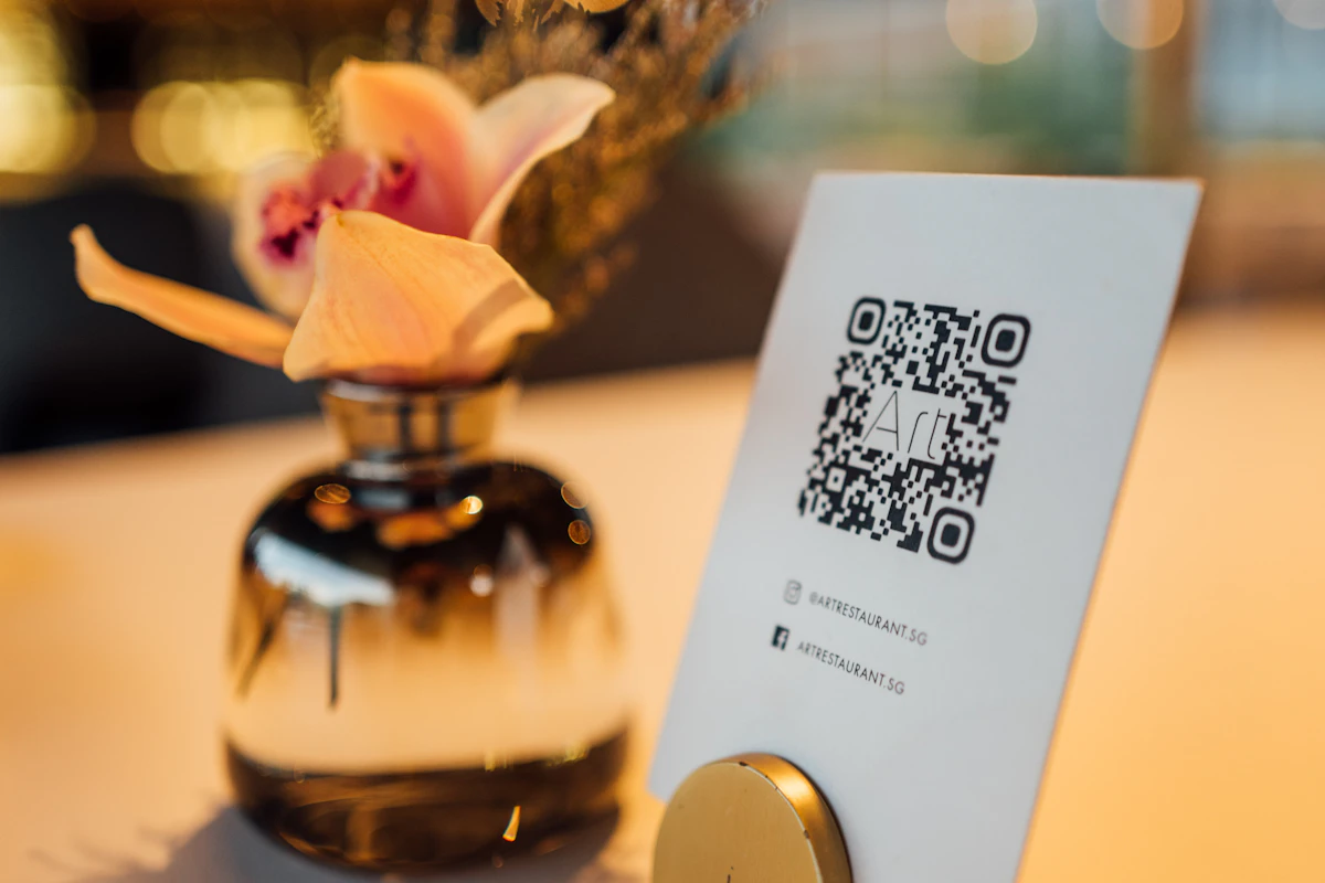 Suporte com código QR numa mesa de restaurante ao lado de uma jarra com flores