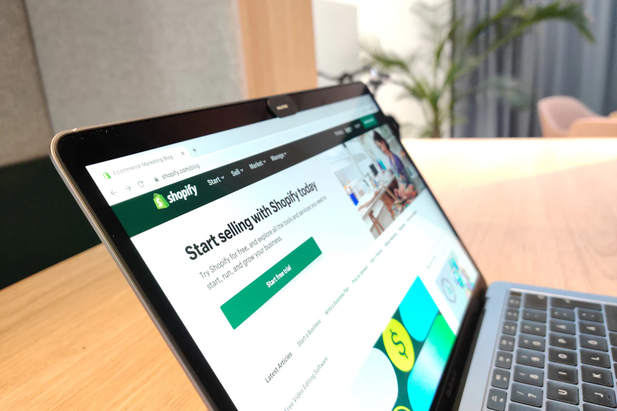 Portátil aberto numa mesa de madeira com a página inicial da Shopify no ecrã
