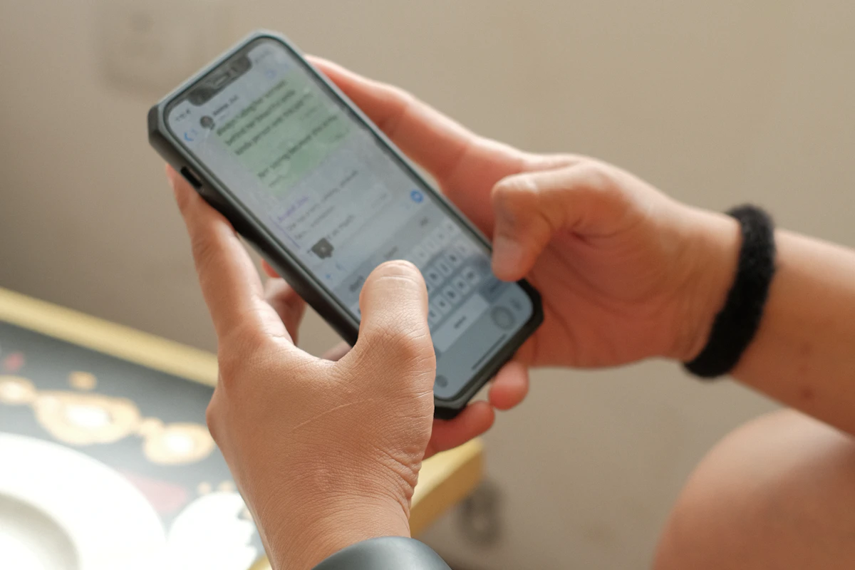 Mãos a escrever numa conversa de WhatsApp no telemóvel