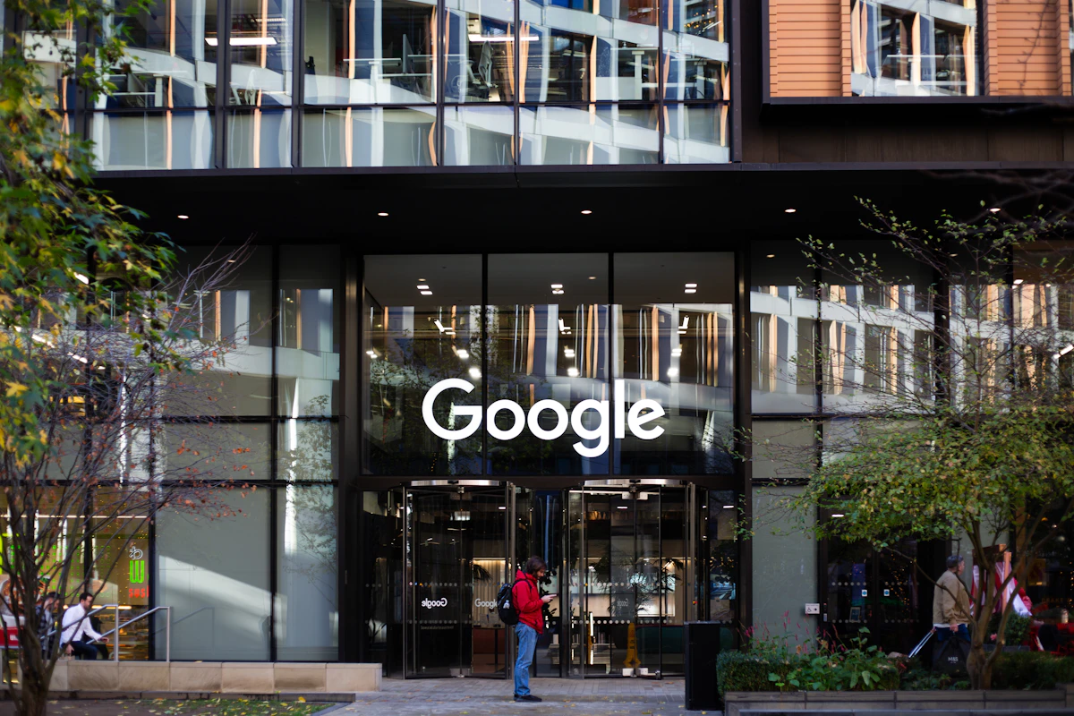 Fachada de um edifício da Google com o logótipo à entrada e pessoas a passar na rua