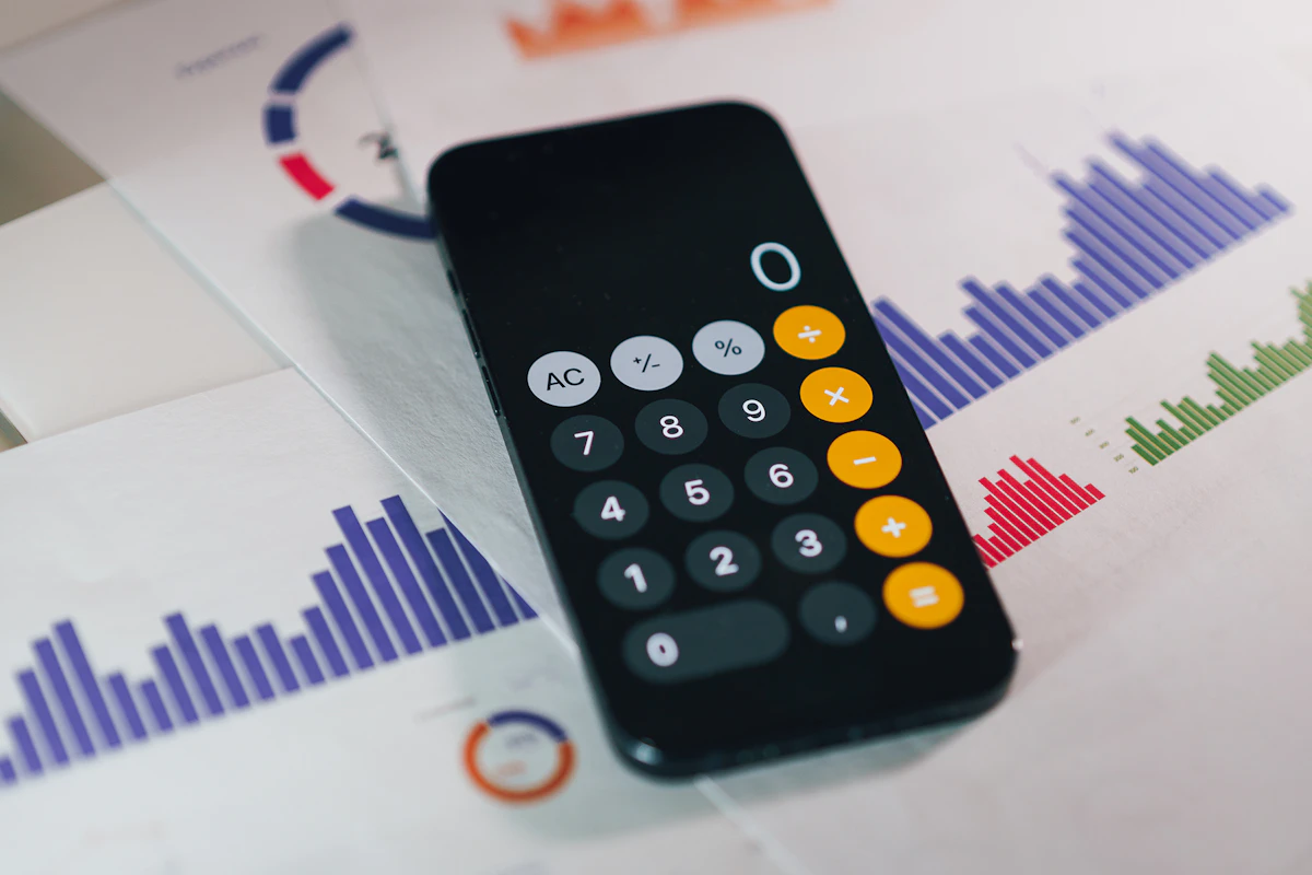 Calculadora de telemóvel pousada sobre relatórios financeiros com gráficos