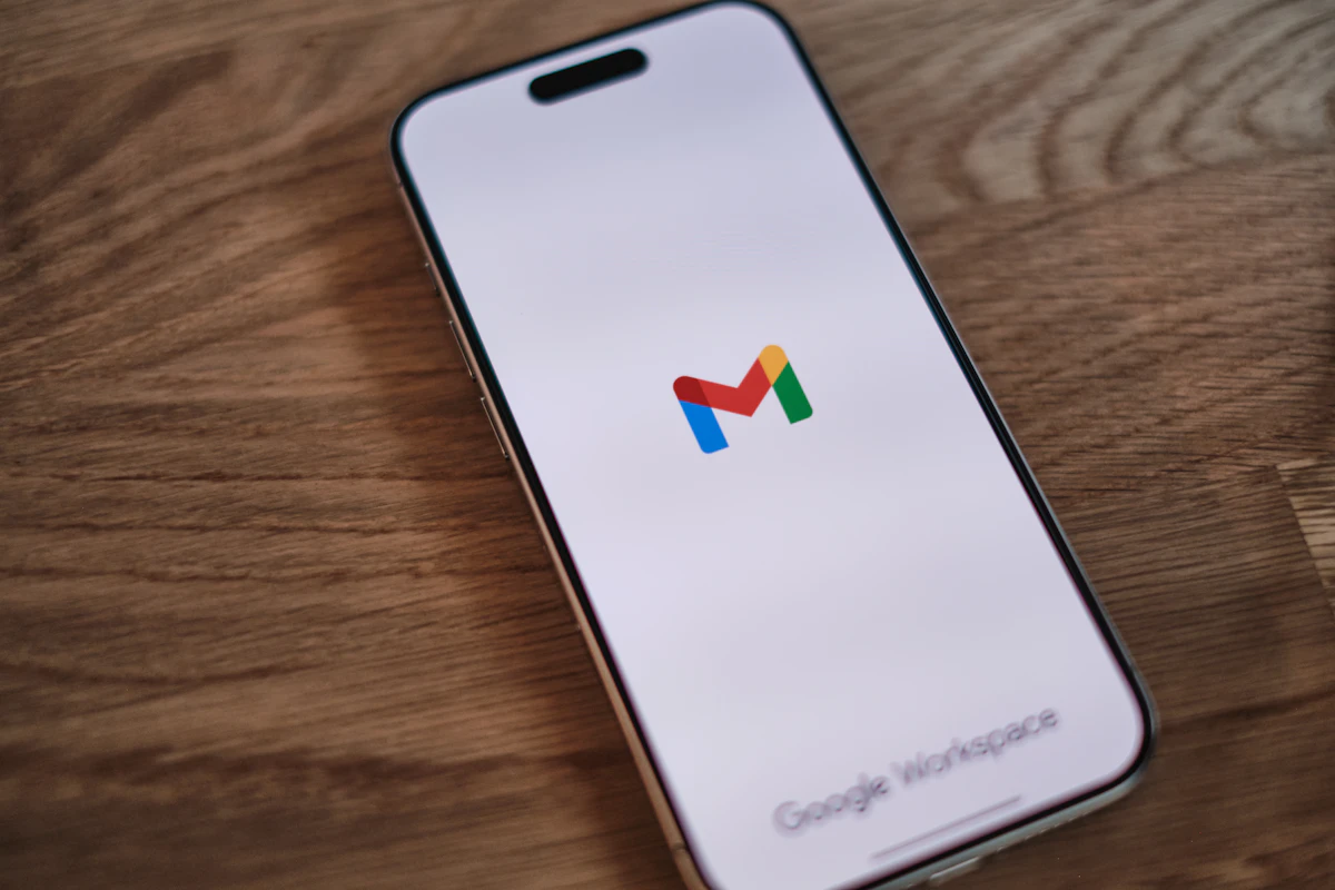 Telemóvel pousado numa mesa de madeira com o logótipo do Gmail no ecrã