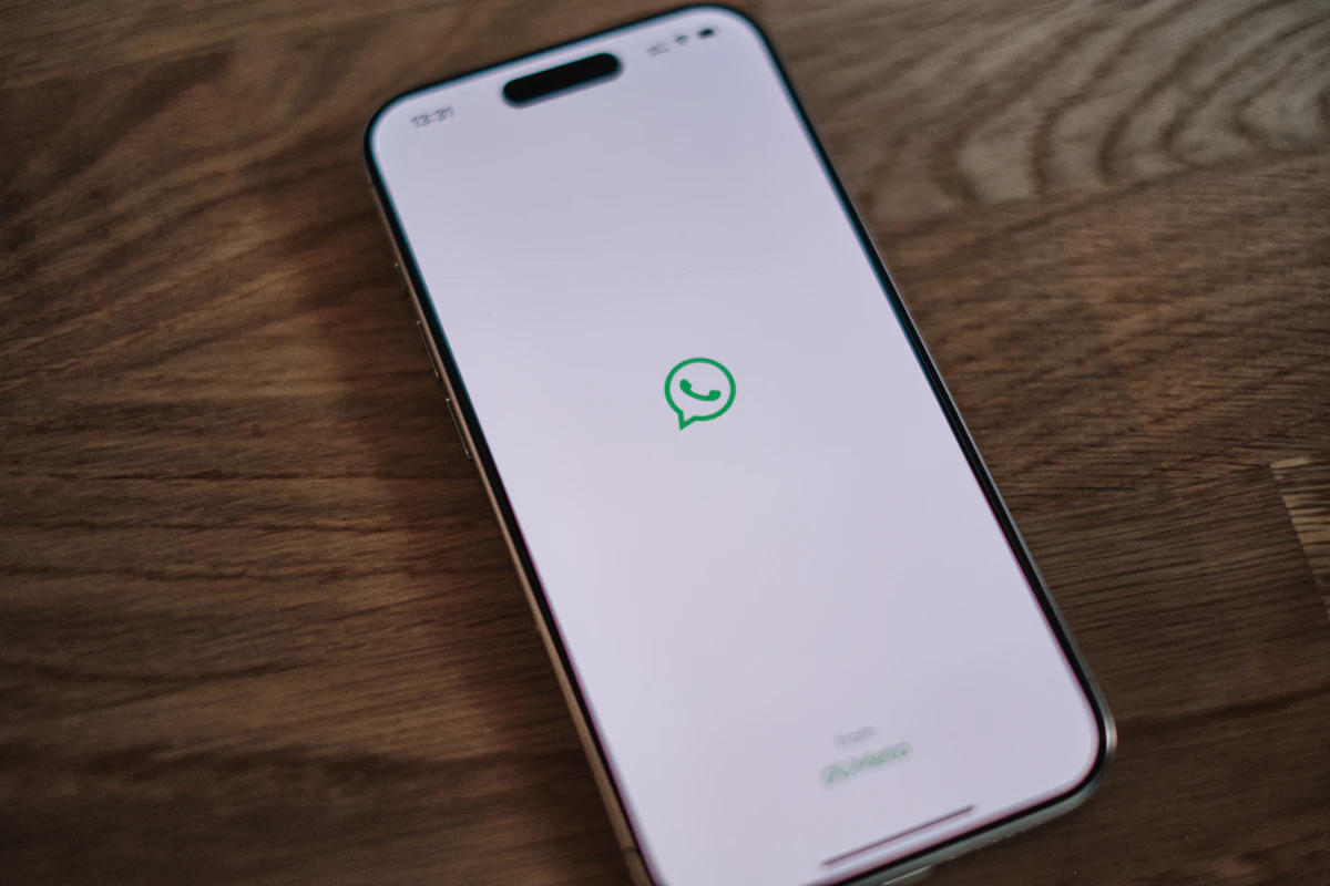 Telemóvel pousado numa mesa de madeira com o ícone do WhatsApp no ecrã