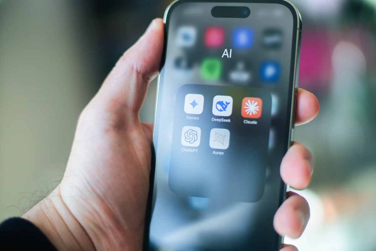Mão a segurar um telemóvel com uma pasta de apps de IA aberta no ecrã