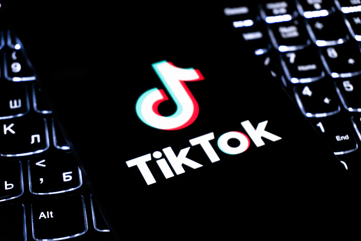 Telemóvel com o logótipo do TikTok pousado junto a um teclado