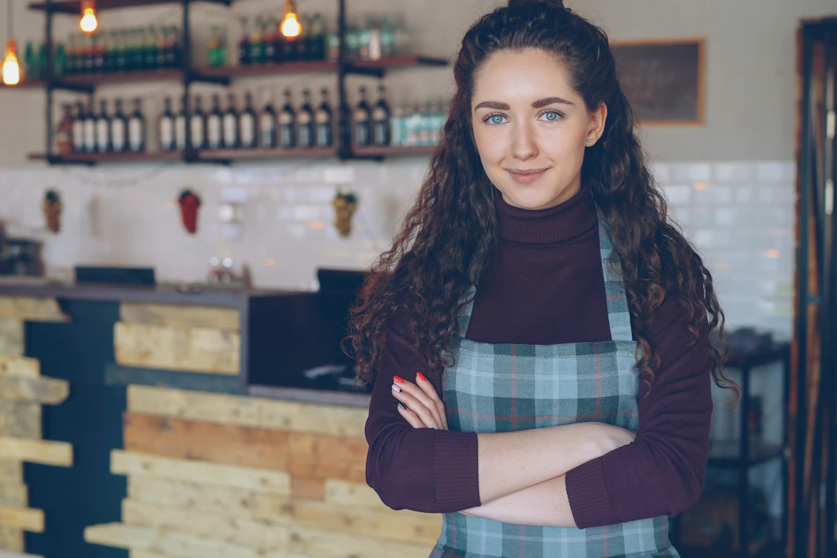 Dona de um café sorridente de pé no seu espaço
