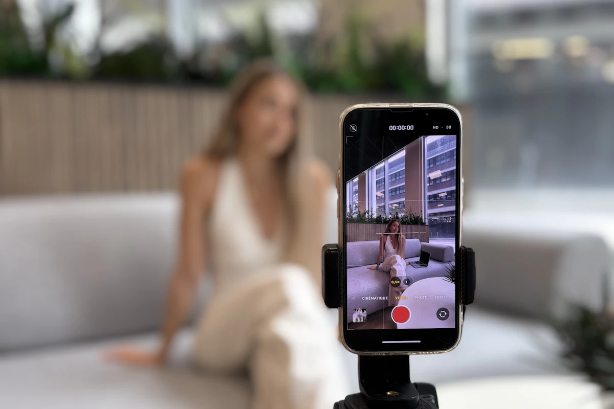 Criadora de conteúdo a gravar-se com o telemóvel num tripé