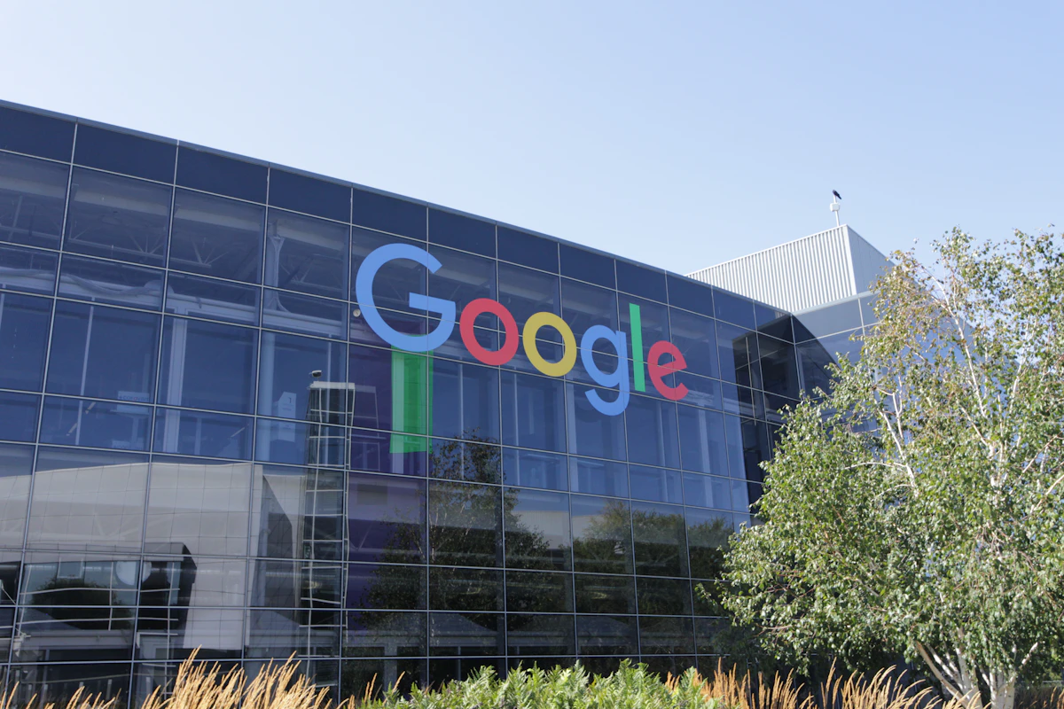 Edifício da sede da Google com o logótipo colorido na fachada e árvores à frente