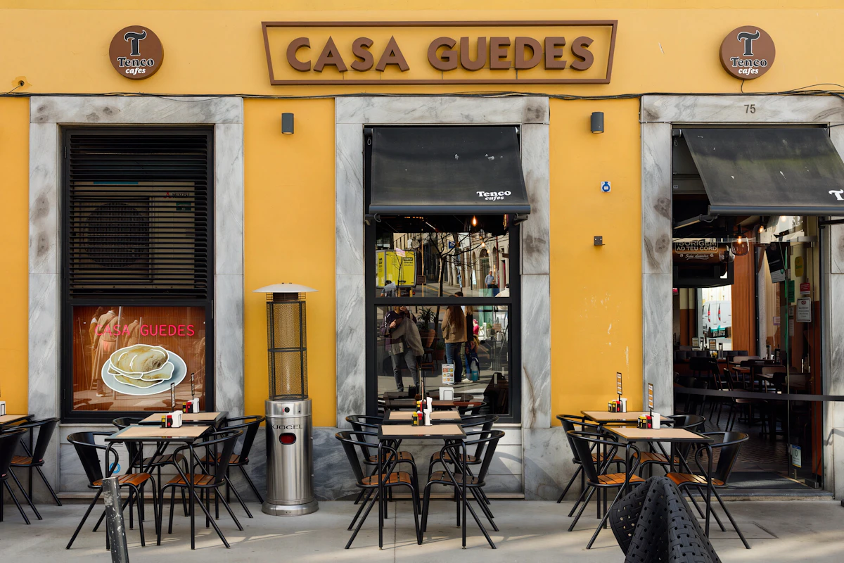 Fachada amarela do restaurante Casa Guedes, no Porto, com esplanada