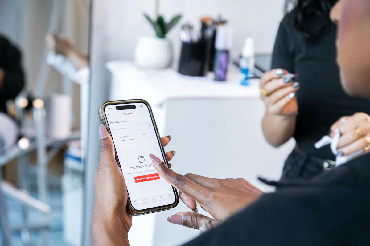 Mãos de uma cliente a fazer uma marcação numa app no telemóvel, num salão de beleza